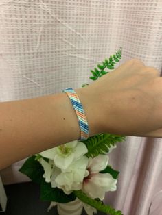 a woman's arm with a bracelet on it and flowers in front of her