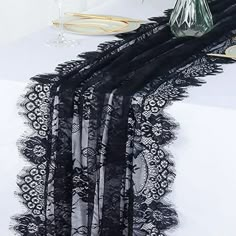 the table is set with black lace and flowers