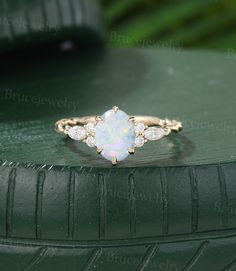 a white opal and diamond ring sitting on top of a green tire treading