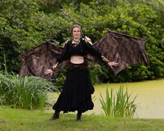 a woman in a black dress is holding a large bat like object above her head