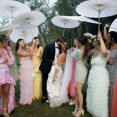 a group of people standing next to each other holding umbrellas in the grass with trees behind them