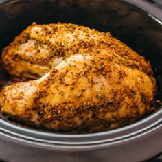 a close up of a chicken in a crock pot with seasoning on it