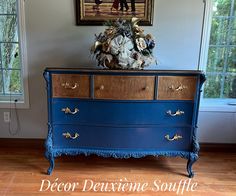 an old dresser painted blue and gold with flowers on top in front of a window