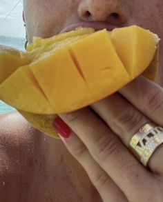 a close up of a person eating a piece of food near the water's edge