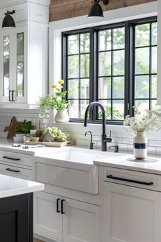 a kitchen with white cabinets and black windows