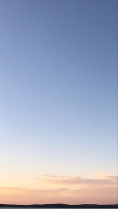 two people are standing on the beach with surfboards in their hands and one person is flying a kite