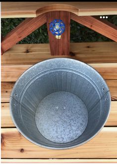 a metal bucket sitting on top of a wooden bench