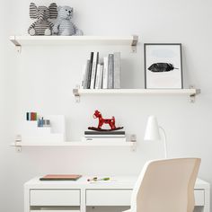 a white desk and chair in a room with shelves on the wall above it,