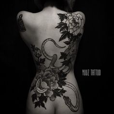 the back of a woman's body with flowers on it and snake tattoo design