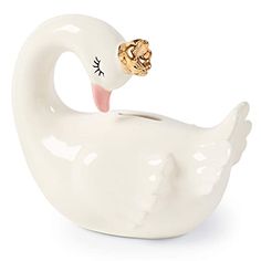 a white ceramic swan figurine with a gold crown on its head and eyes