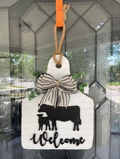 a welcome sign hanging from the side of a glass door with a cow on it