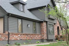 a house with gray shingles and red brick