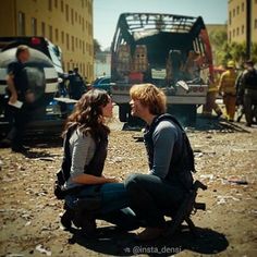 a man and woman sitting next to each other in front of a truck on the road