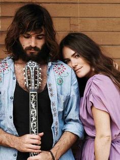 a man and woman standing next to each other with a guitar in their hands,