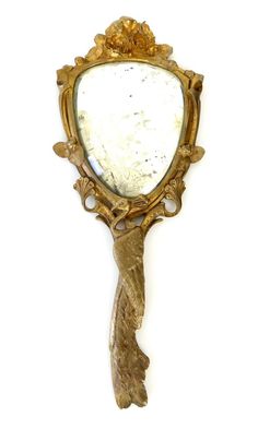 an ornate mirror hanging on the wall with a gold leaf decoration around it's edge