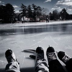 two people standing on an ice rink with their feet propped up against the skating surface