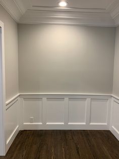 an empty room with white paneling and wood floors