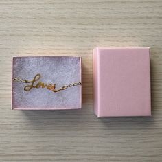 a pink box with the word love written on it and a gold chain in front of it