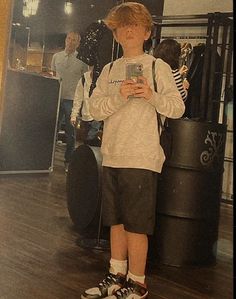 a young boy standing in front of a mirror looking at his cell phone