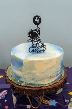 a cake that is on top of a purple table cloth and has an astronaut design on it