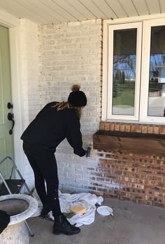 a woman painting the outside of a house