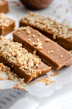 pieces of chocolate with nuts on top sitting next to a knife