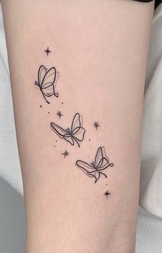 a small tattoo with three butterflies flying in the sky and stars on it's side