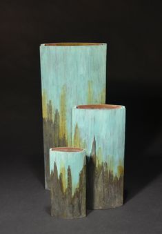 three vases are sitting side by side in front of a black background and one has a city skyline painted on it