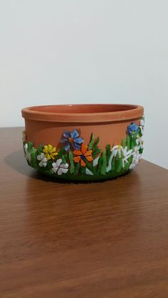 a flower pot sitting on top of a wooden table next to a planter with flowers painted on it