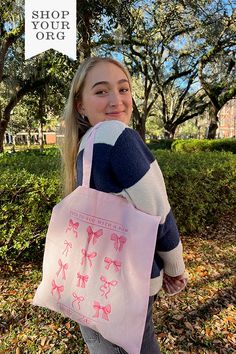 a woman carrying a pink shopping bag with bows on it and the words shop your org