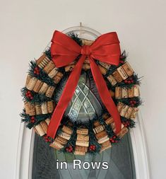 a wreath made out of wine corks with a red bow on the front door