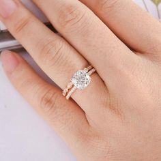 a woman's hand with a diamond ring on top of her finger and the other hand holding a cell phone