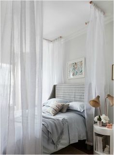 a white bedroom with sheer curtains and a bed