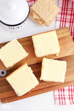 four pieces of cheesecake on a cutting board next to crackers