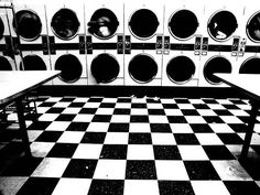 a black and white checkered floor in a public laundment with rows of washers