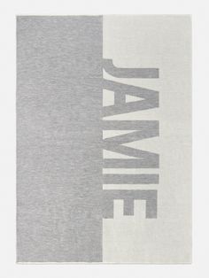 a gray and white towel with the word jamie on it's back side, in front of a plain background