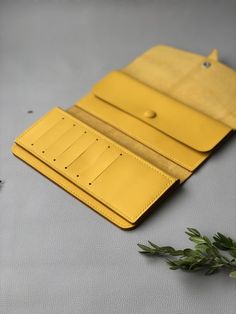 a yellow leather wallet sitting on top of a table next to a green leafy plant