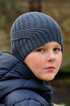 a young boy wearing a knitted hat and jacket with the words tenth wave written on it