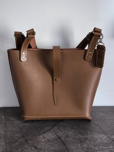 Welcome to SpearCraftShop! Experience timeless elegance and practicality with our handmade, hand-stitched leather tote bag. Designed in a large size with classic hazelnut color, this tote is perfect for daily use, offering ample space and a chic design. With dimensions of 30 cm in height, 38 cm width at the top, 28 cm width at the bottom, and 11 cm depth, it combines functionality with sophisticated style. Crafted from premium leather and featuring durable hand stitching, this bag is built to la Brown Bucket Satchel With Top Carry Handle, Brown Everyday Satchel With Top Carry Handle, Daily Brown Satchel Bucket Bag, Large Brown Shoulder Bag With Top Carry Handle, Daily Brown Tote Satchel, Large Brown Satchel With Top Carry Handle, Handmade Bucket Satchel For Everyday Use, Everyday Brown Bucket Bag Tote, Large Brown Satchel