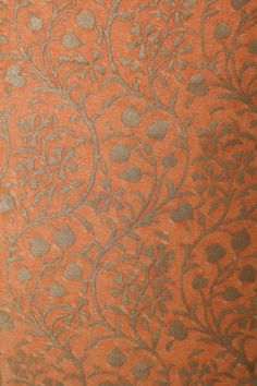 an orange and silver wallpaper with floral designs on the back side, in shades of grey