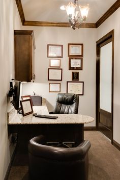 an office with a desk, chair and pictures on the wall