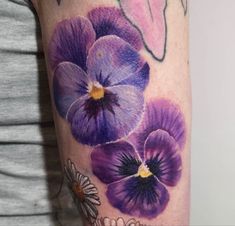 a woman's arm with purple flowers painted on it and daisies in the background