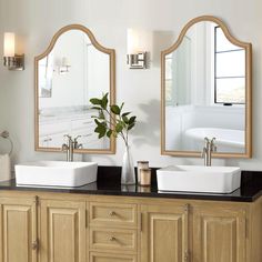 a bathroom with two sinks, mirrors and a vase on the counter top in front of it