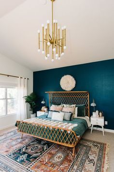 a bedroom with blue walls, gold bed frame and chandelier hanging from the ceiling