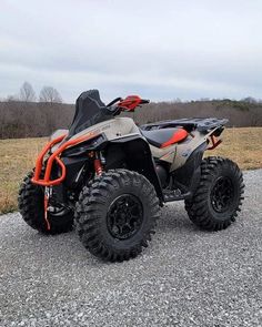 an orange and black four - wheeler parked on gravel