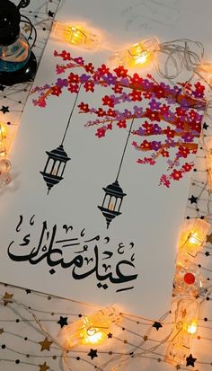 an arabic greeting card with lanterns and stars on the table in front of it is lit by candles