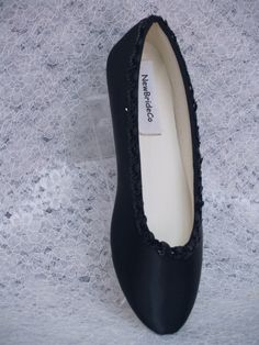 a pair of black slippers on top of a white lace covered surface with a label