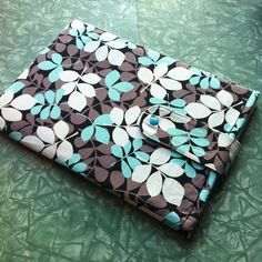 a blue and brown flowered bag sitting on top of a green cloth covered table