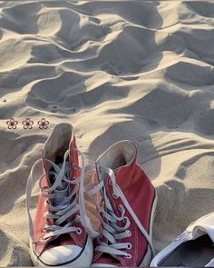 a pair of red shoes sitting on top of a sandy beach next to a shoelace