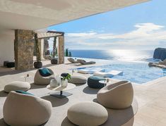 an outdoor lounge area with chairs and tables next to the swimming pool overlooking the ocean